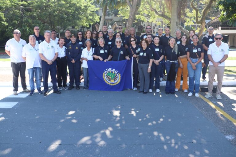Grupo de pessoas reunido com bandeira da ADESG.