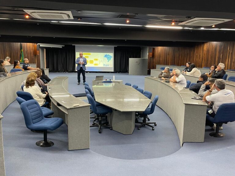 Palestrante em apresentação para grupo em auditório moderno.
