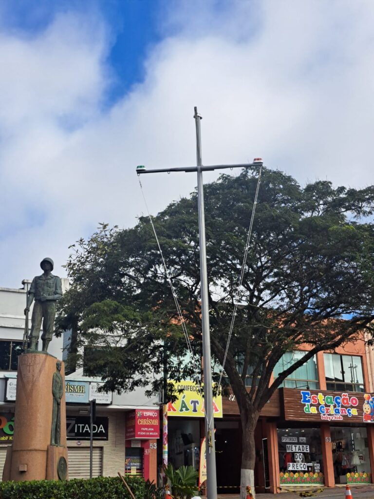 Estátua em praça pública com lojas ao fundo.