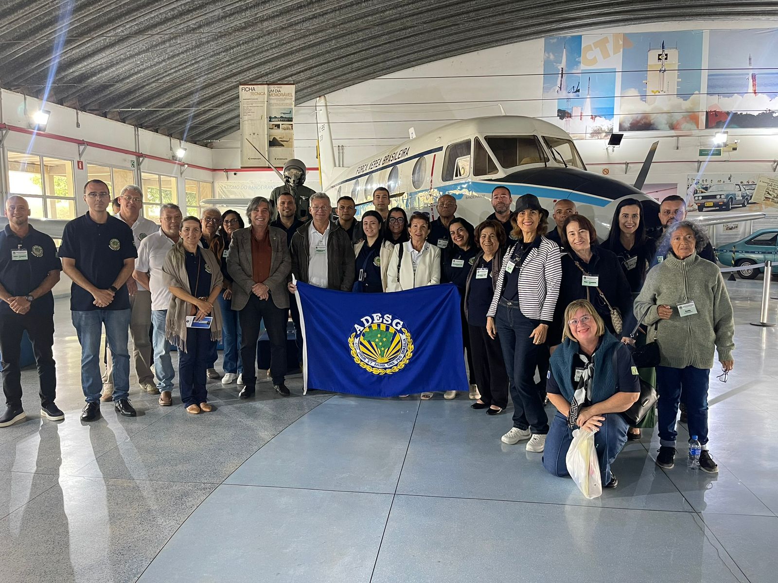 Grupo posa em frente a avião no museu aéreo.