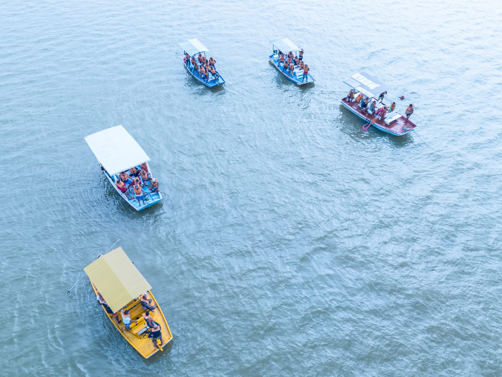 Barcos com turistas navegando em lago sereno.