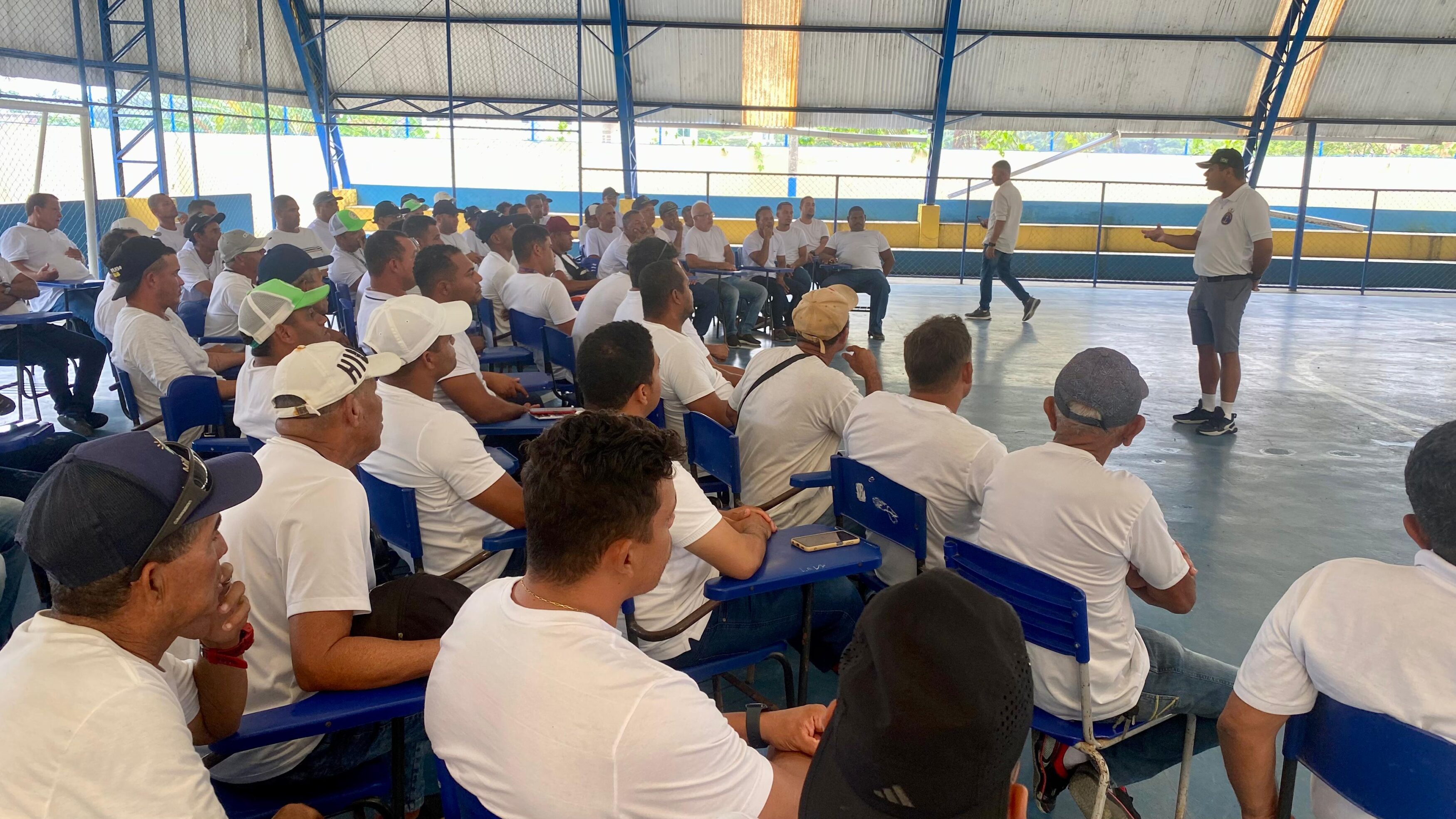 Instrutor fala para grupo de homens em palestra.