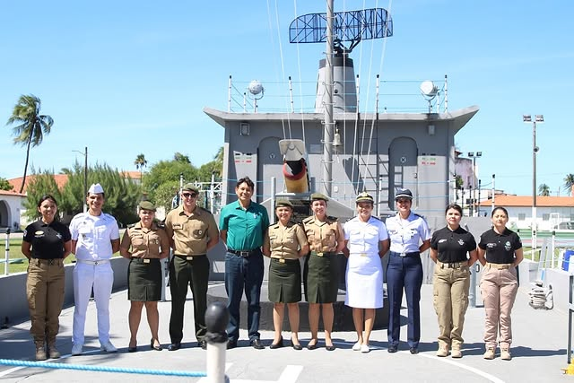 Militares em uniformes posando em frente a embarcação.