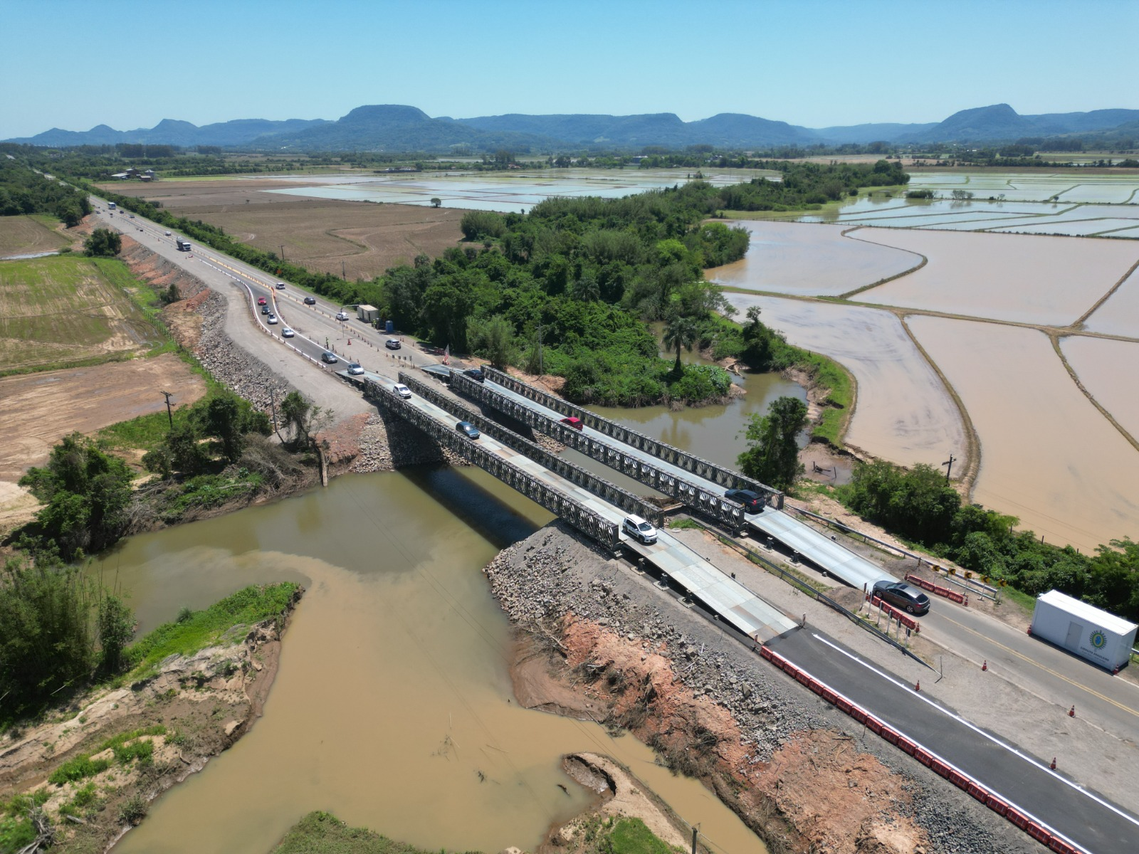 Ponte sobre rio em área rural com carros.