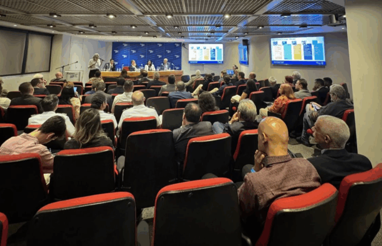 Pessoas assistem a apresentação em auditório.