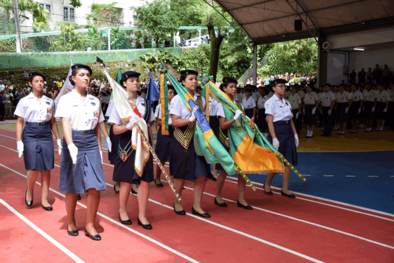 Desfile de estudantes com bandeiras em cerimônia escolar.