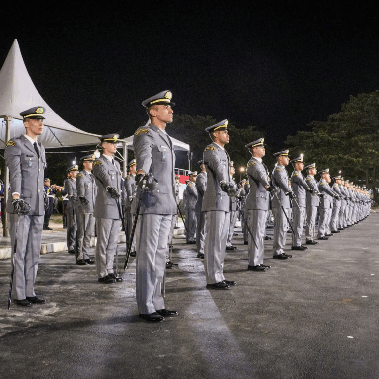 Desfile de cadetes militares em formação noturna.