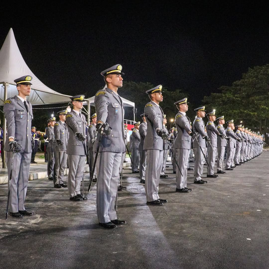 Desfile de cadetes militares em formação noturna.