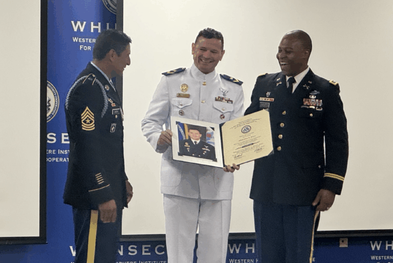 Pessoas em trajes militares segurando certificado em cerimônia.