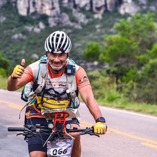Ciclista sorrindo em estrada montanhosa
