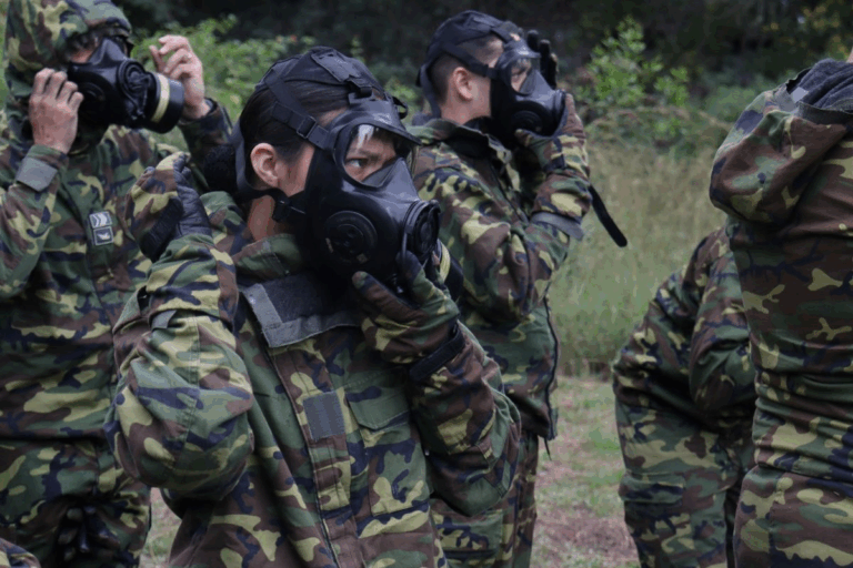 Soldados vestindo máscaras de gás e uniformes camuflados.