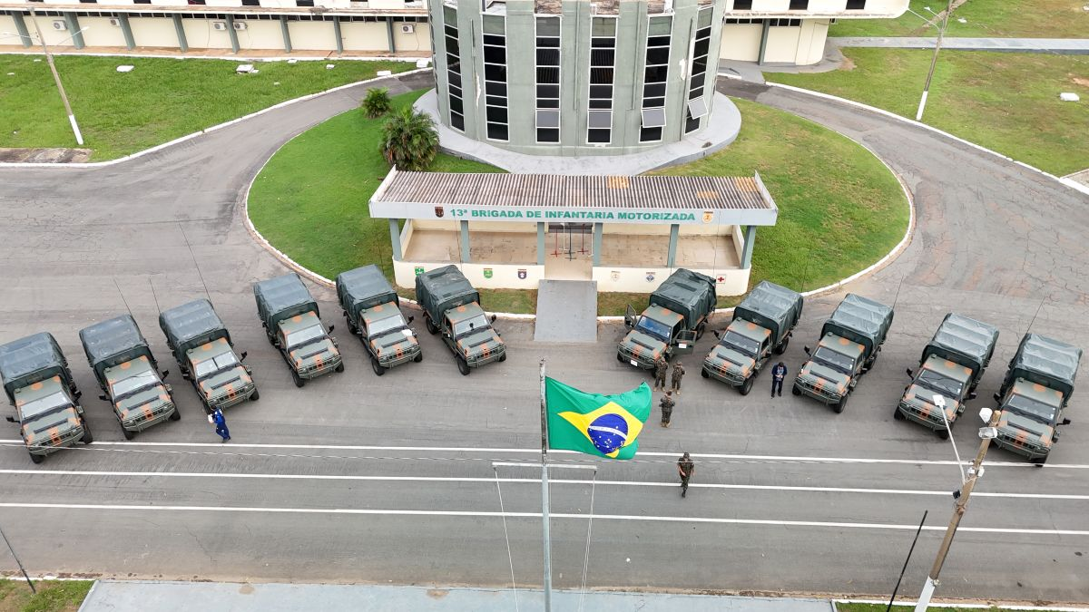 Veículos militares alinhados com bandeira do Brasil.