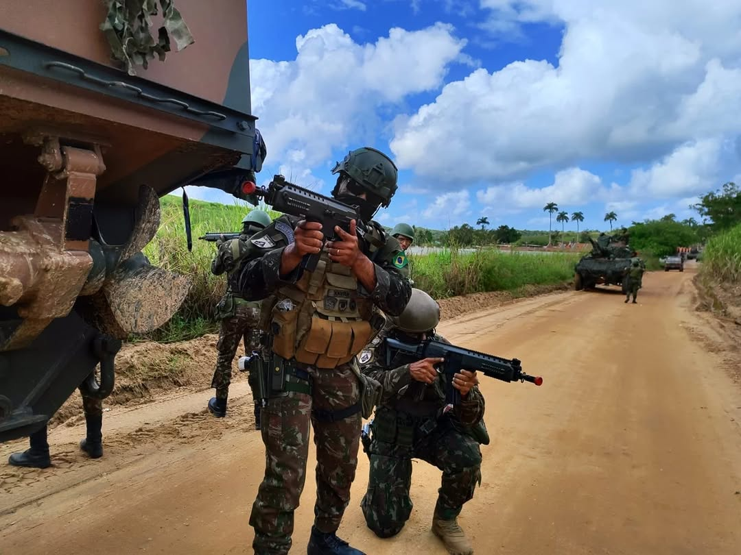 Militares em exercício tático com armas pesadas.