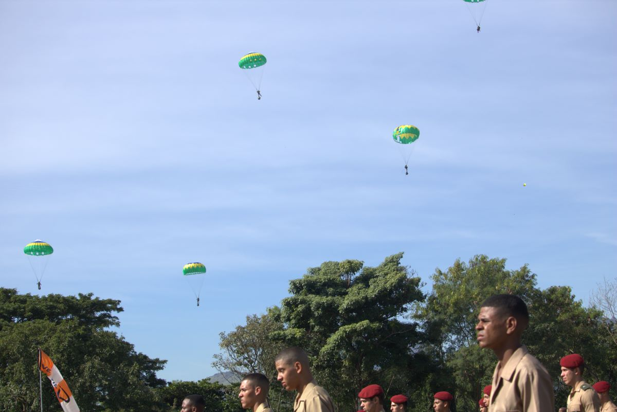 Paraquedistas e soldados em cerimônia militar ao ar livre.