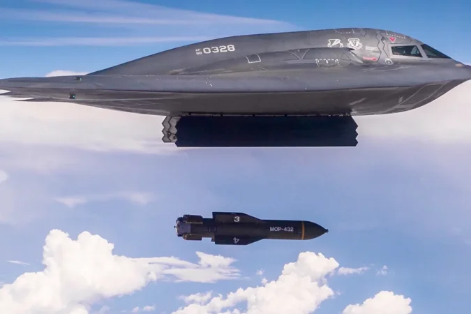 Avião militar soltando bomba em voo.