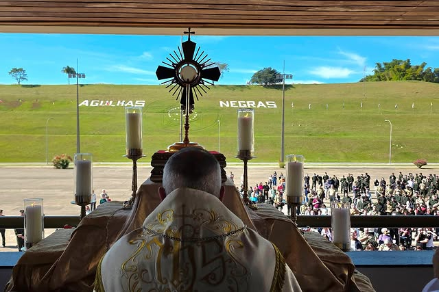 Cerimônia religiosa com fiéis ao ar livre.