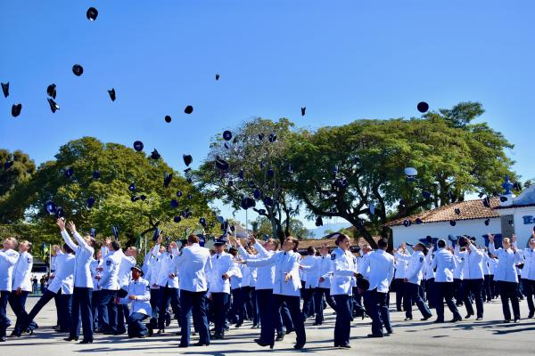 Graduandos jogam chapéus no ar em celebração.
