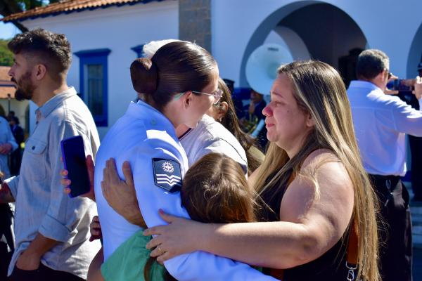 Família abraçando militar em cerimônia ao ar livre.