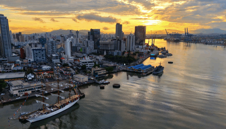 Porto de Santos ao entardecer com céu dourado.