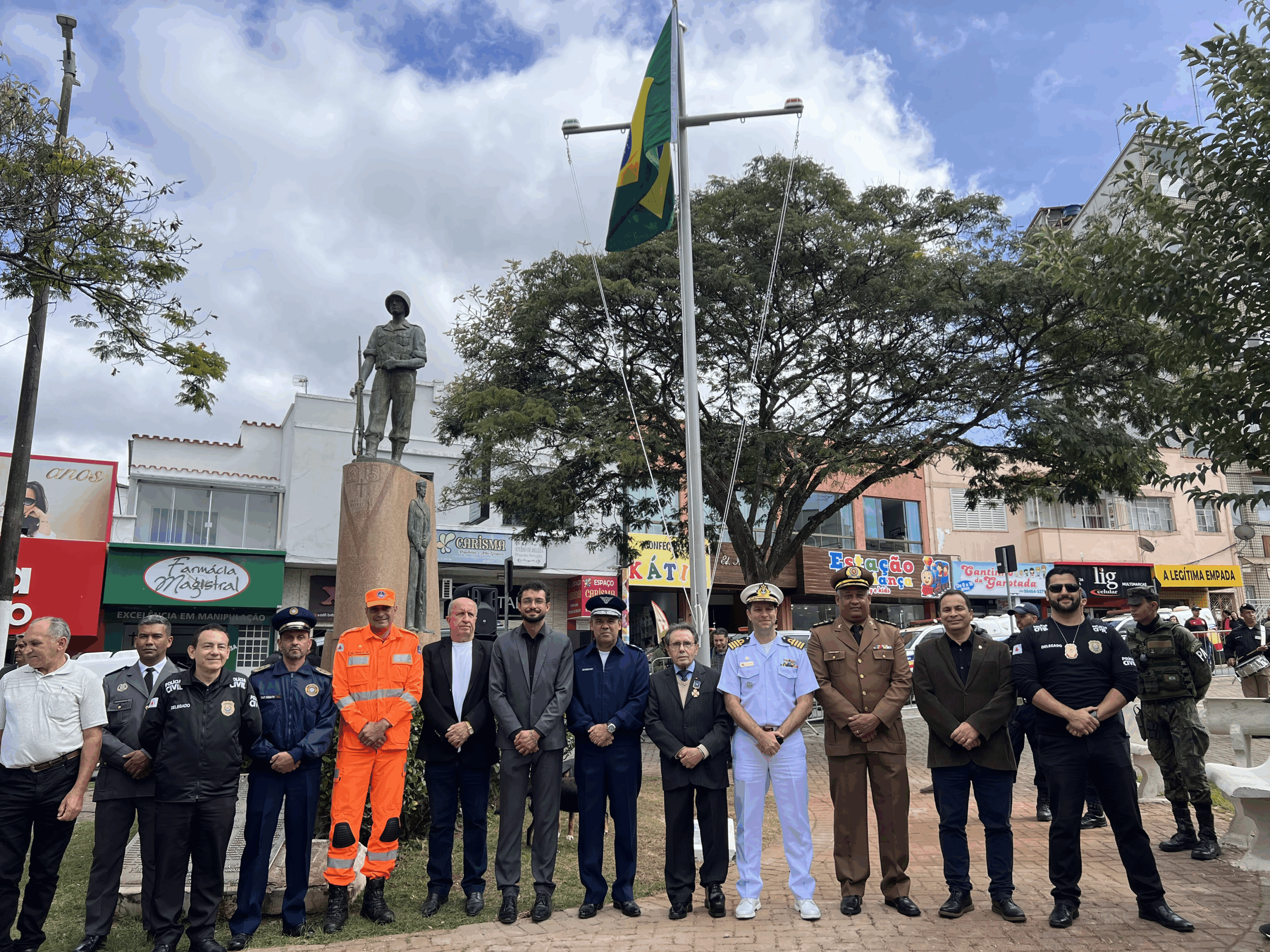 Autoridades em evento público com bandeira do Brasil.