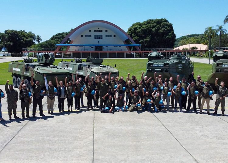 Grupo de pessoas posando com veículos militares.