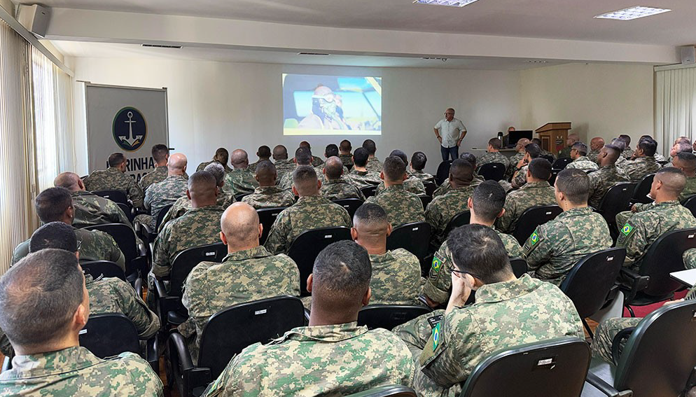 Soldados assistem apresentação em sala de conferência.