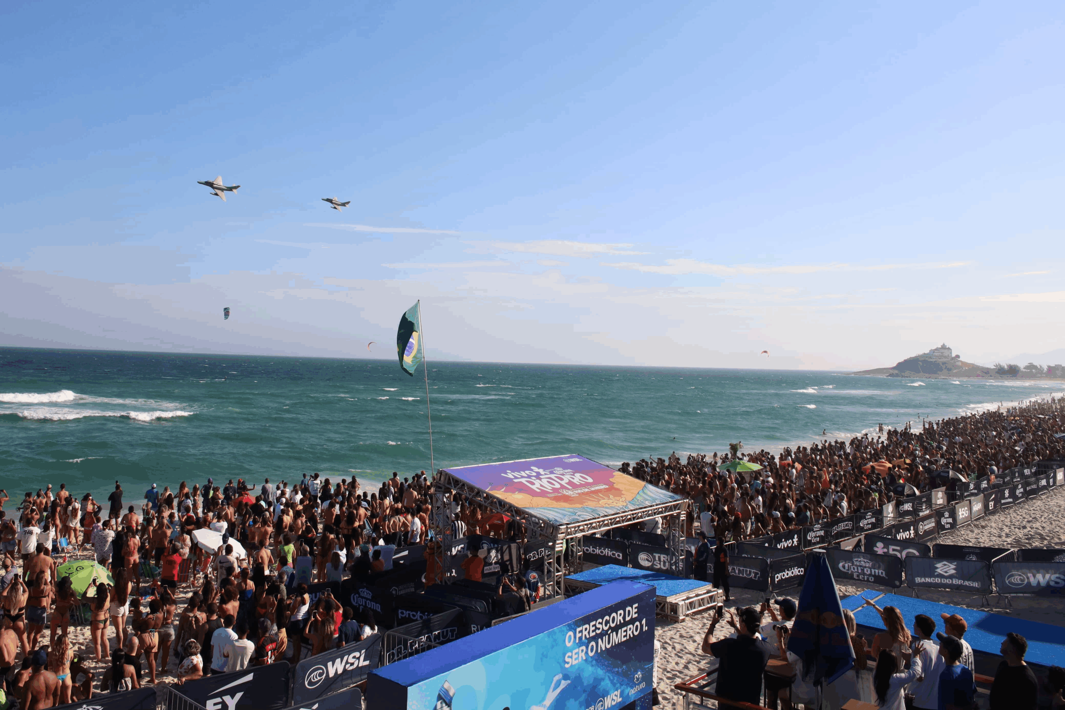 Multidão na praia com aviões sobrevoando