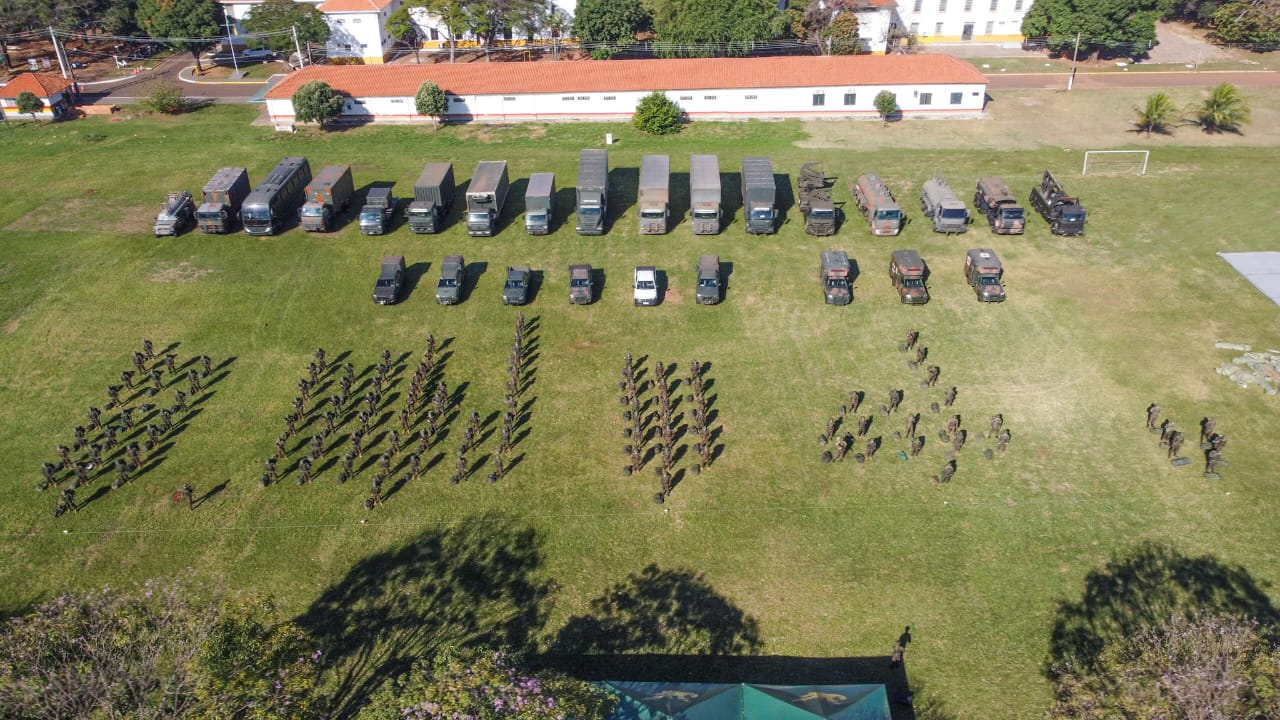 Exercício militar com veículos e soldados reunidos.
