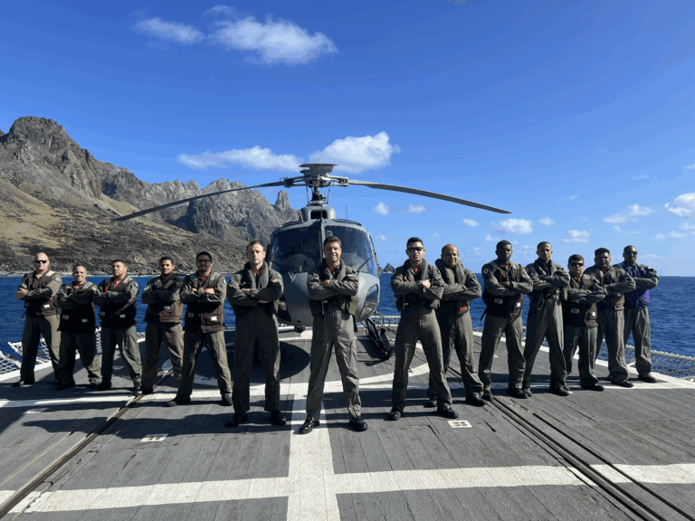 Tripulação de pilotos com helicóptero no convés do navio.