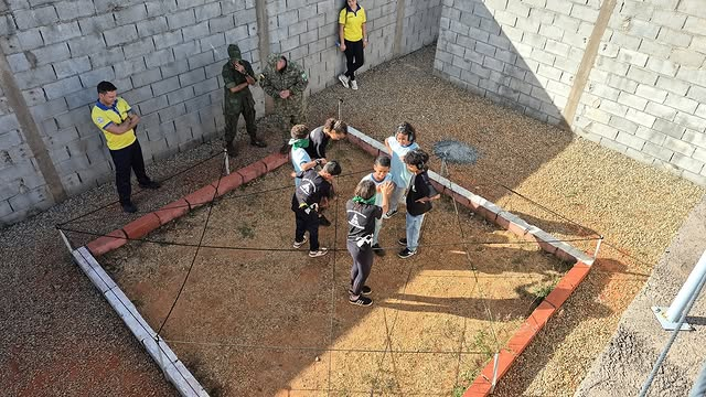 Grupo participa de atividade em área cercada, ao ar livre.