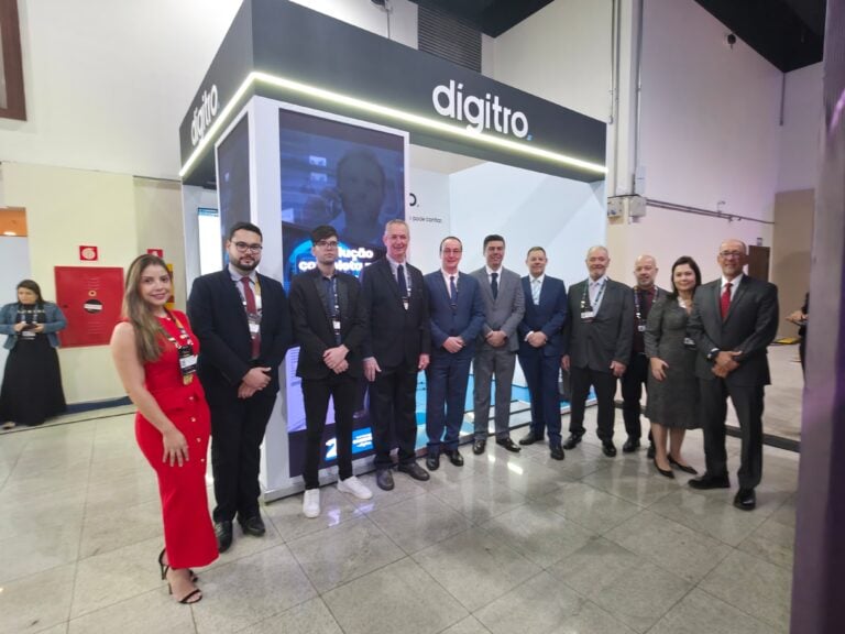 Pessoas em frente ao estande da Digitro em evento.