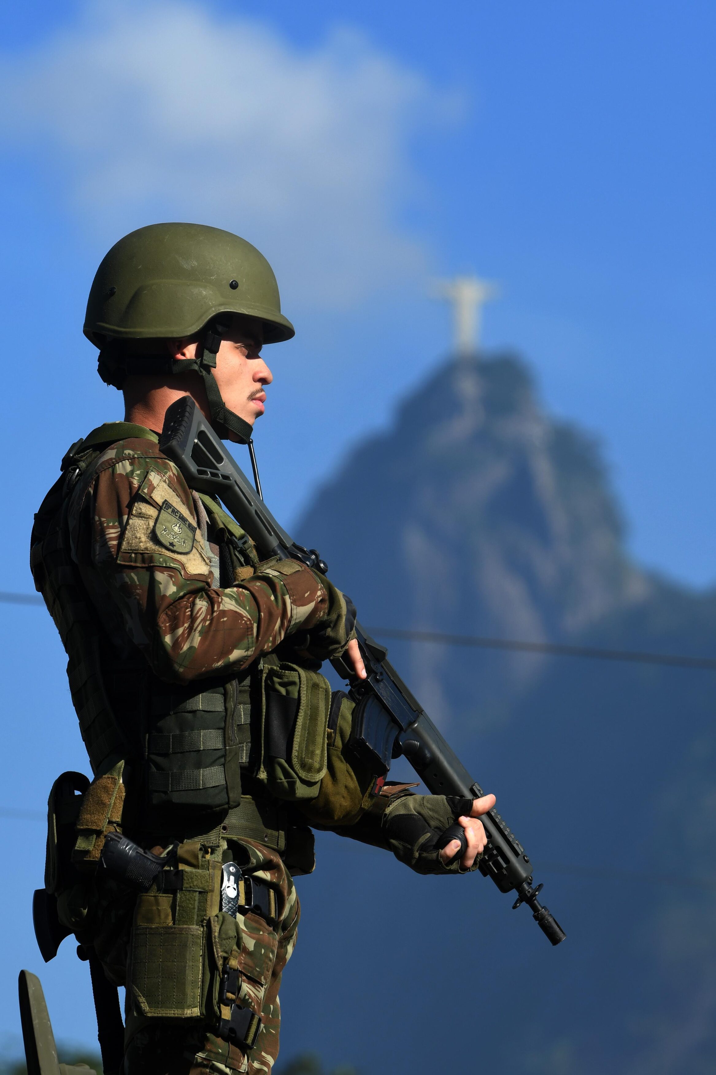 Soldado armado frente ao Cristo Redentor no Rio.