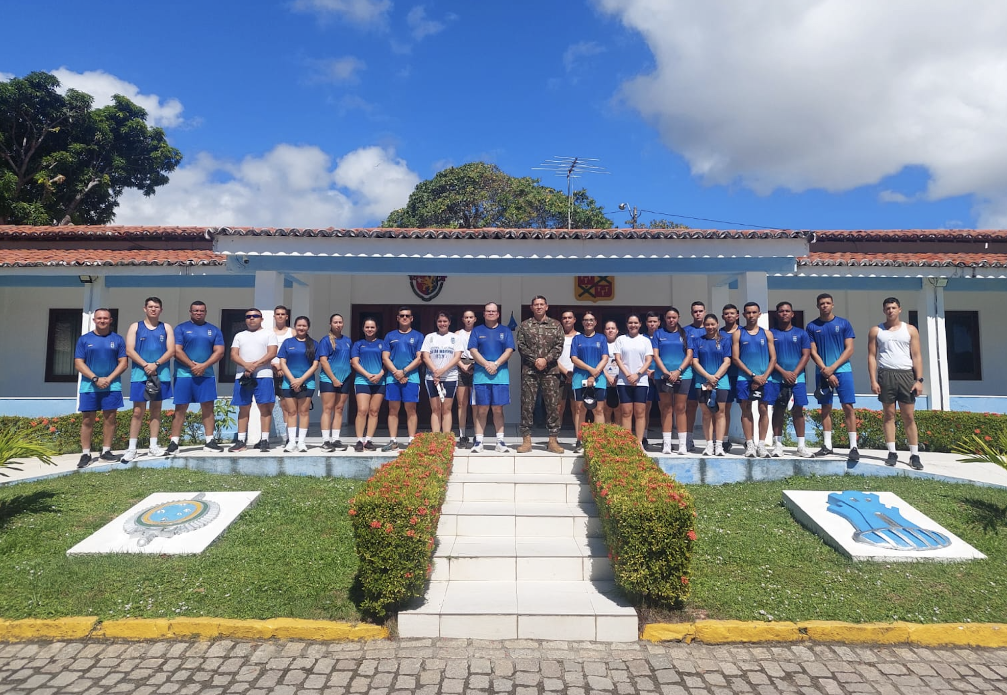 Grupo de pessoas uniformizadas em frente a prédio militar.