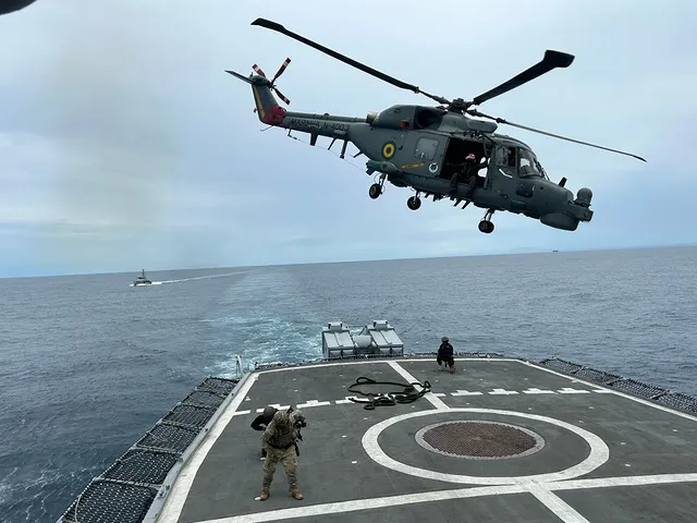 Helicóptero sobrevoa convés de navio em alto mar.