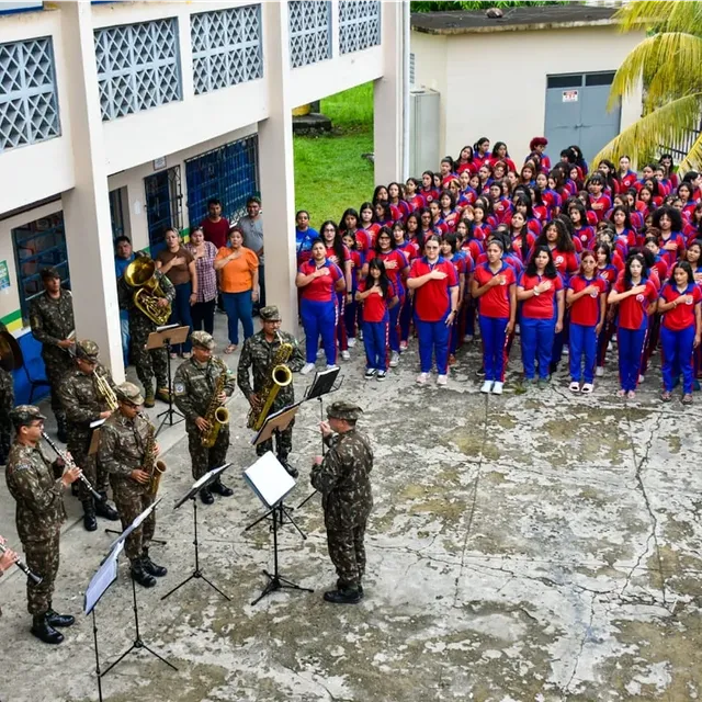 Banda militar se apresentando para estudantes em escola.