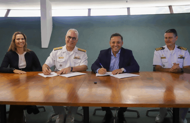 Pessoas assinando documentos em uma mesa.