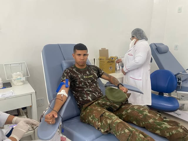 Homem fardado doando sangue em clínica médica.