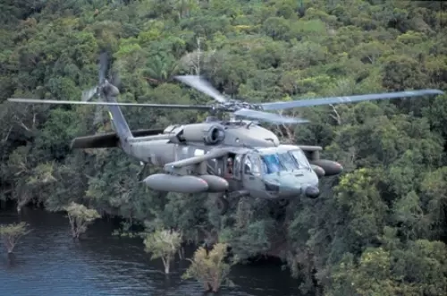 Helicóptero militar sobrevoa floresta densa.