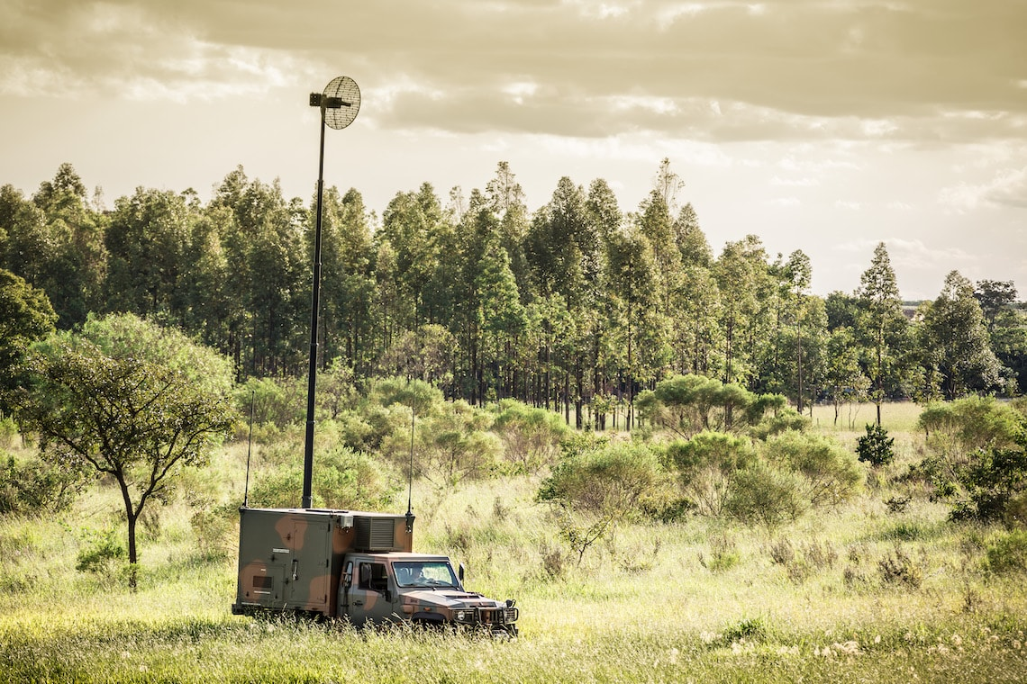 Veículo militar com antena em campo verde