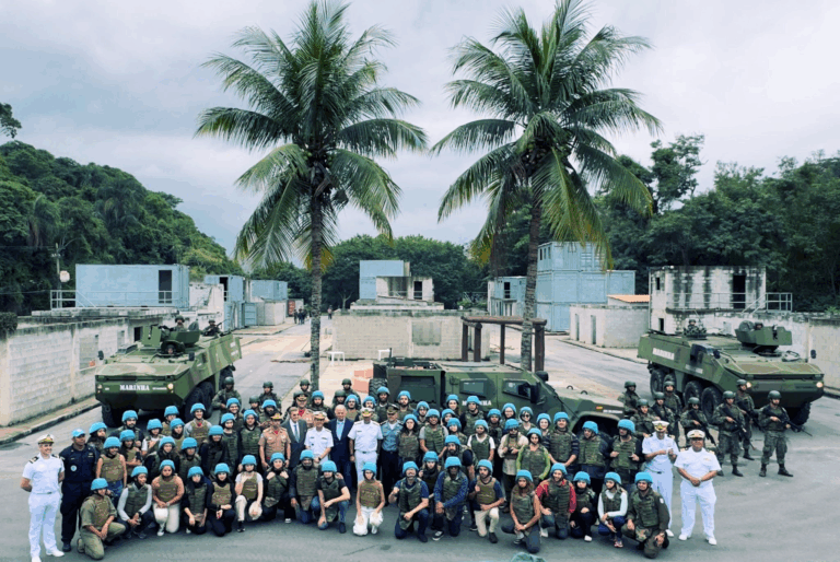 Grupo militar e civil em base com tanques.