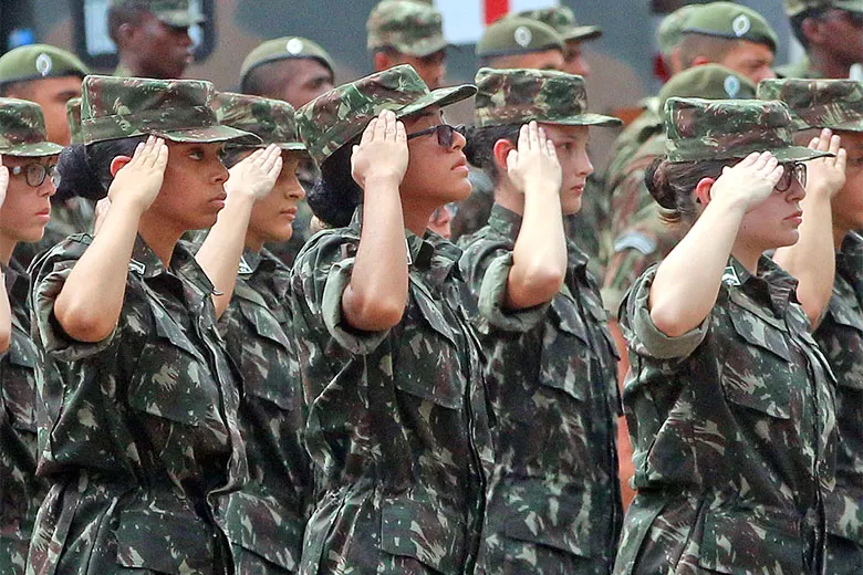 Soldados mulheres em uniforme militar prestando continência.