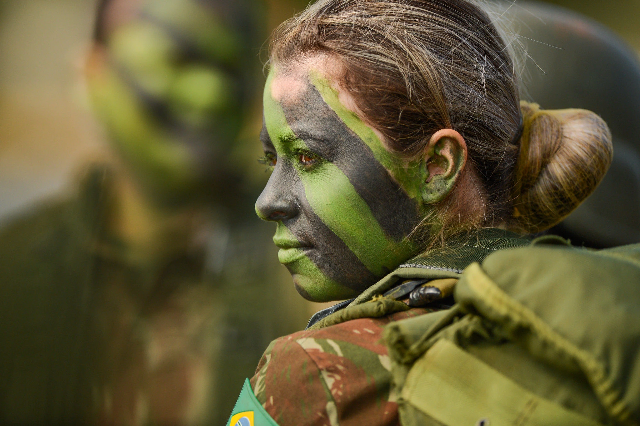 Soldado brasileira com pintura de camuflagem verde.