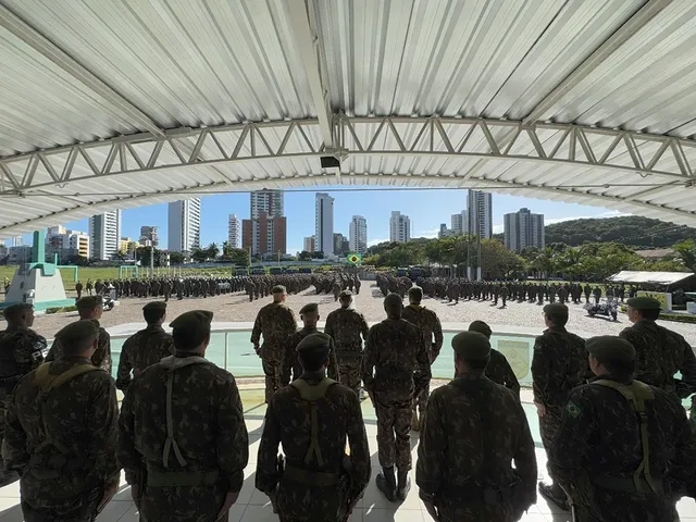 Soldados em formação com cidade ao fundo.