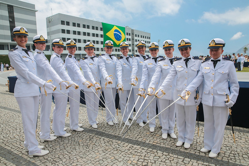 Militares brasileiras em formatura, uniformes brancos, Bandeira do Brasil.
