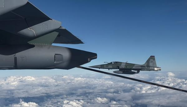 Avião reabastecendo em pleno voo sobre nuvens.