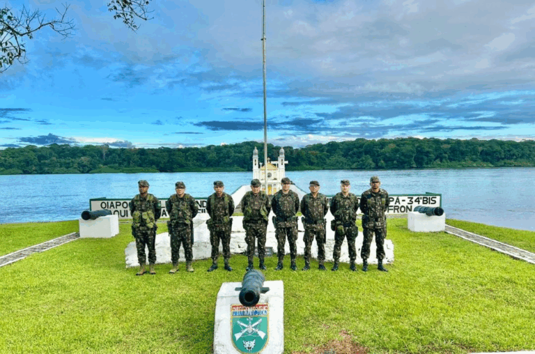 Soldados posando em frente ao rio, céu azul.
