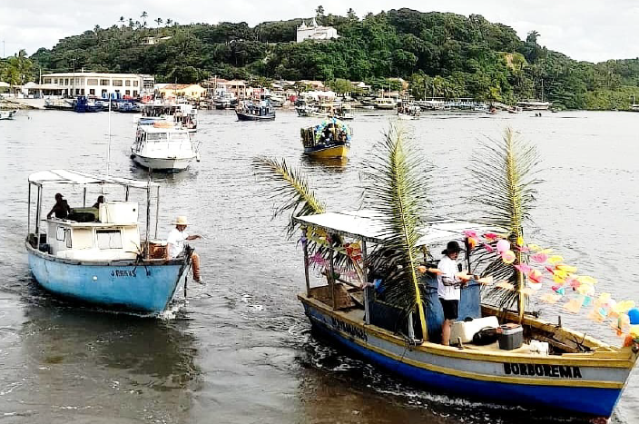Barcos decorados em rio com vegetação ao fundo.