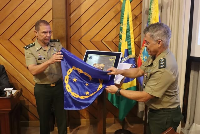 Militares exibem bandeira com medalha em evento.