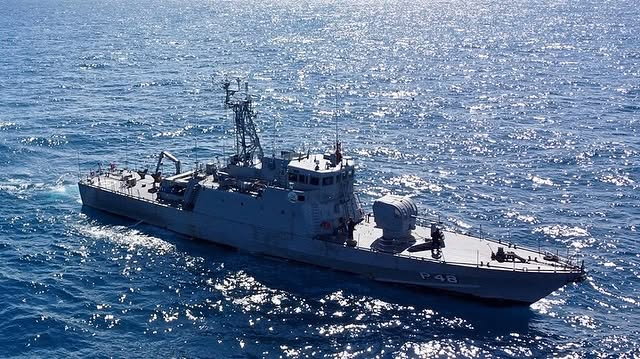 Navio de guerra navegando em mar aberto, dia ensolarado.