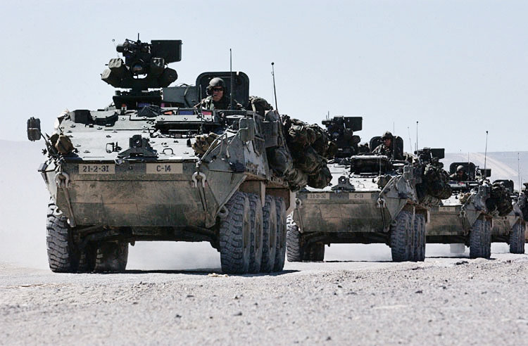 Veículos militares blindados em movimentação no deserto.
